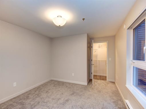 a bedroom with a large window and a door to a bathroom
