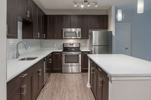 A modern kitchen with dark brown cabinets and stainless steel appliances.