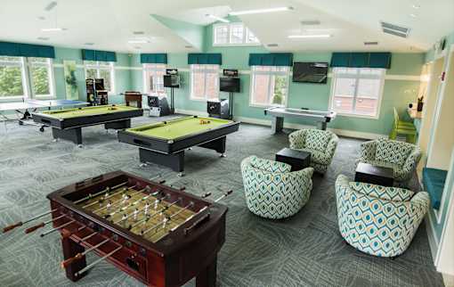 A room with a foosball table and a pool table.