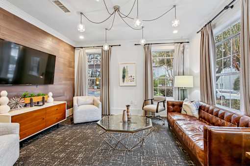 A living room with a brown leather couch and a glass coffee table.