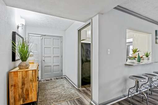 A room with a wooden cabinet, a potted plant, and a mirror on the wall.