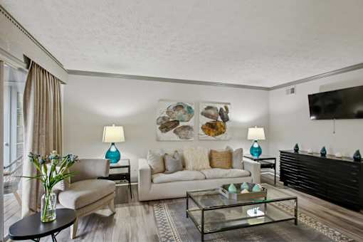 A living room with a white couch, a glass coffee table, and a painting on the wall.