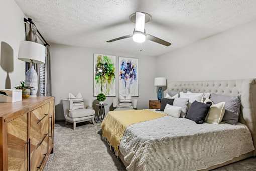 A bedroom with a large bed and a painting on the wall.