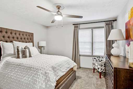 A bedroom with a large bed and a ceiling fan.