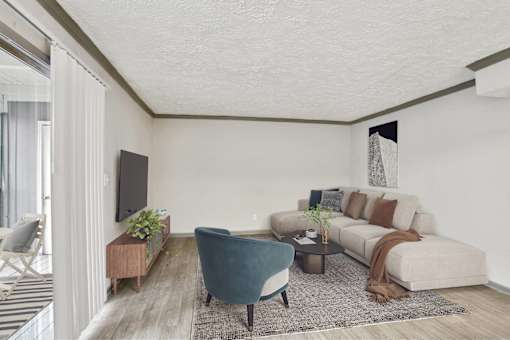 A living room with a blue armchair, a grey sofa, and a wooden side table.