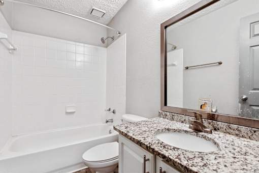 A white bathroom with a tub, toilet, and sink.