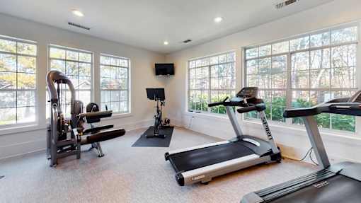 A home gym with a treadmill, elliptical trainer, and a stationary bike.