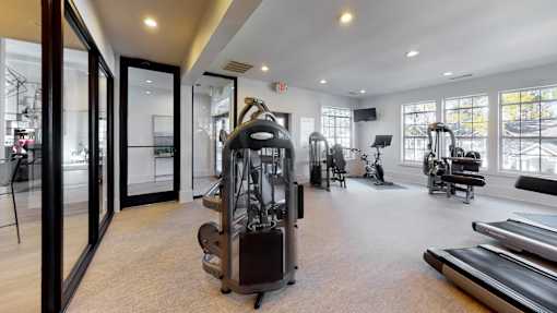 A gym with a variety of equipment including treadmills, weights, and exercise machines.