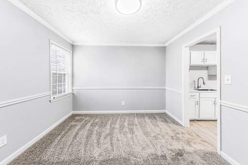 A room with a carpeted floor and a window with blinds.