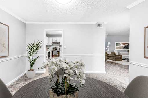 A white room with a plant and a vase of flowers on a table.