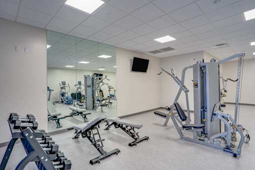 a gym with exercise equipment and mirrors in a building
