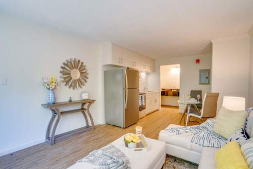 a living room with a white couch and a stainless steel refrigerator