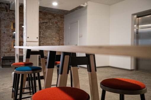 A row of three stools with different colored cushions are in front of a white wall.