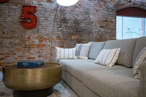 A living room with a couch, a coffee table, and a number 5 on the wall.