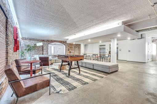 A room with a brick wall and a long table with chairs.