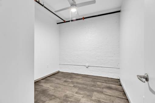A room with a ceiling fan and a wooden floor.