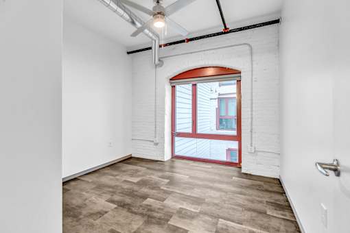 A room with a ceiling fan and a door leading to a balcony.
