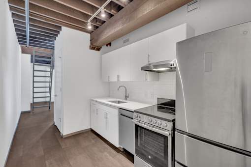 A modern kitchen with white cabinets and stainless steel appliances.