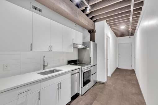 A kitchen with white cabinets and a wooden ceiling.
