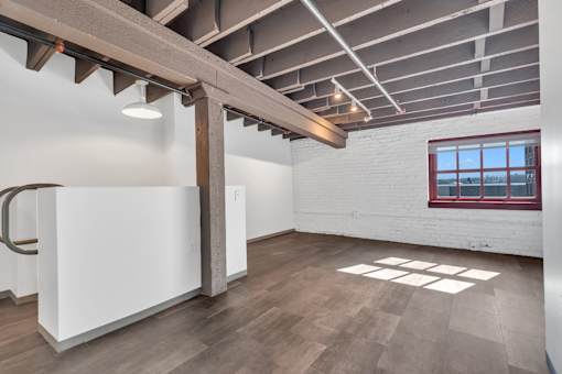 A room with a white wall and a window with a red frame.