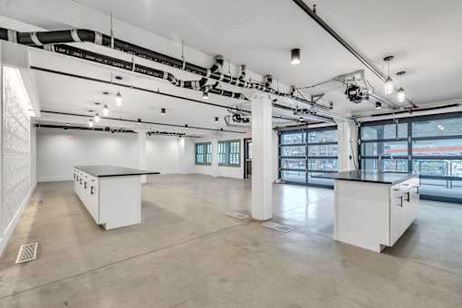 A large, empty room with white cabinets and a concrete floor.