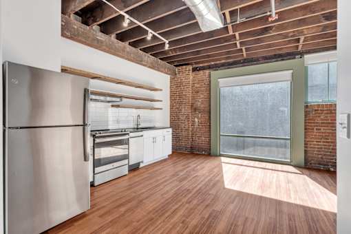 A kitchen with a refrigerator, oven, and wooden floors.