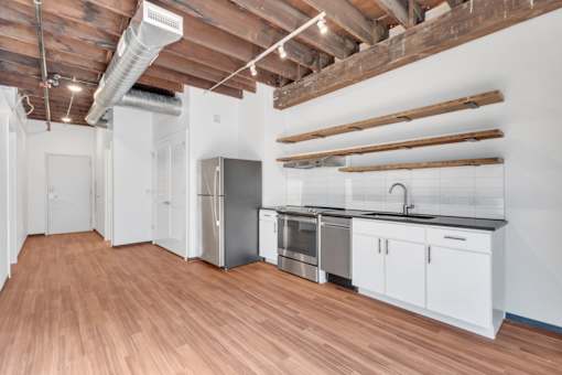 A kitchen with white cabinets and a wooden floor.