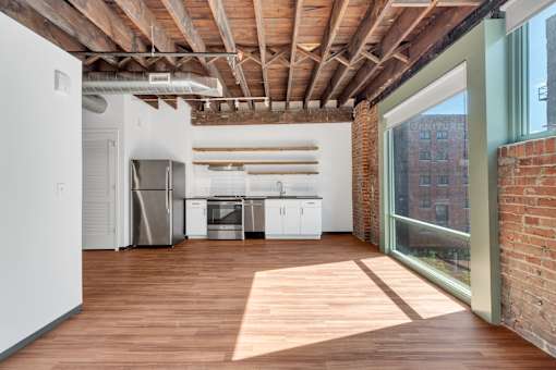 A kitchen with wooden floors and a brick wall.