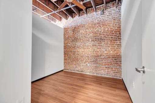 A room with a brick wall and wooden floor.