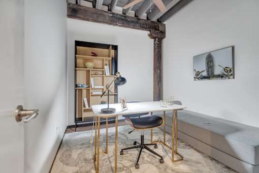 A room with a desk, chair, and a picture on the wall.