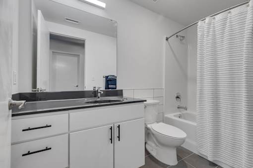 A white bathroom with a sink, toilet, and shower.