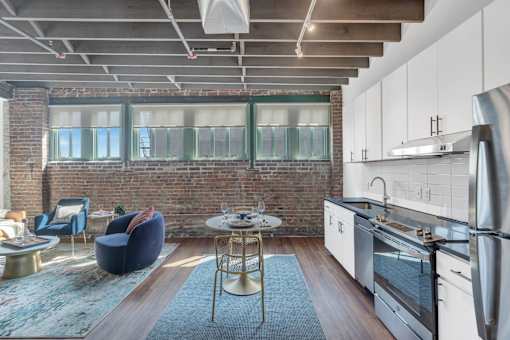 A modern kitchen with a brick wall and a dining table with chairs.