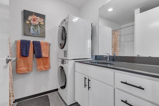 A laundry room with a washer and dryer, a sink, and a mirror.