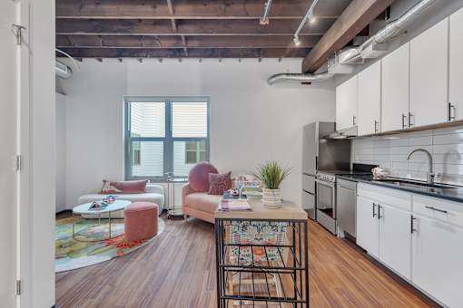 A kitchen with white cabinets and a wooden floor.
