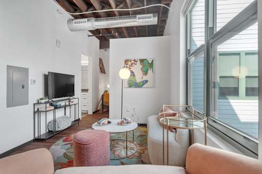 A living room with a television, a couch, and a rug.