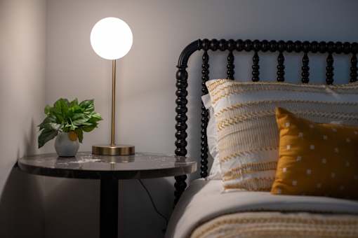 A bed with a white pillow and a lamp on a side table.
