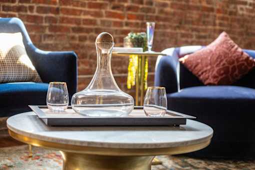 A table with a tray, a decanter, and two glasses on it.