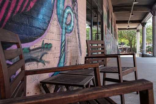 A mural of a face is painted on a wall behind a bench.