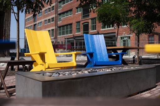 Two chairs, one yellow and one blue, are placed on a concrete platform.