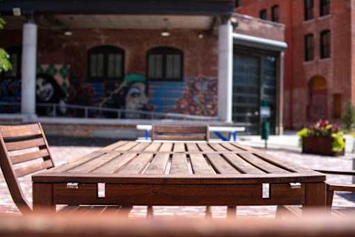 A wooden table is in the foreground of a building with graffiti.