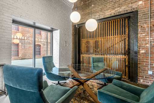 A room with a brick wall and a glass table with chairs.