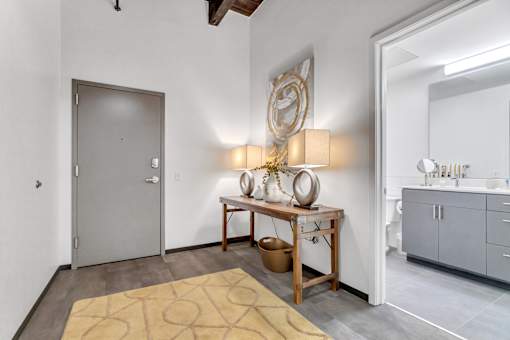A room with a grey door and a table with a vase and a plant on it.