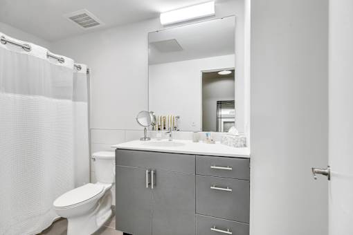 A bathroom with a white toilet, sink, and cabinet.