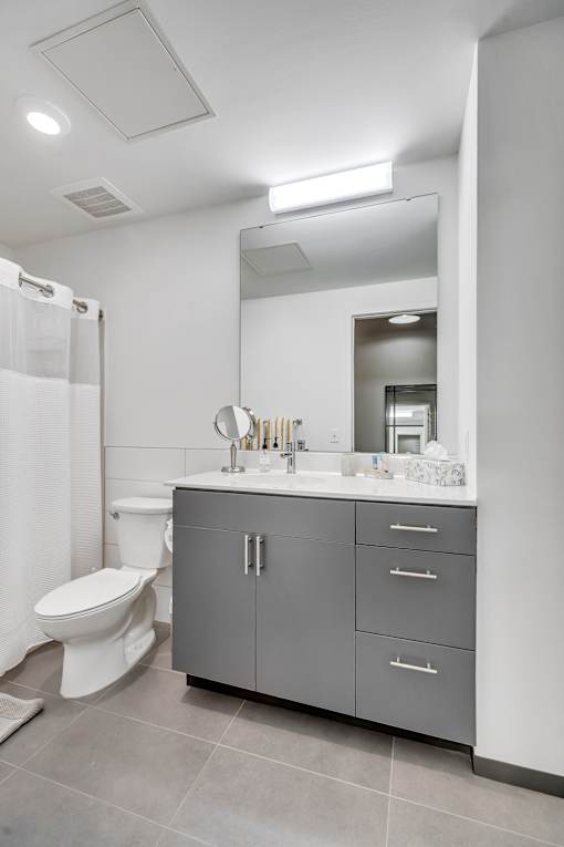 A bathroom with a toilet, sink, and mirror.