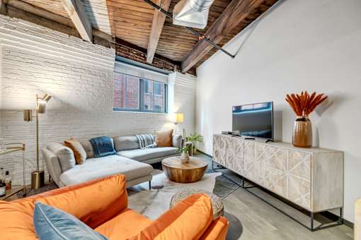 A living room with a white brick wall and a wooden ceiling.