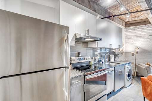A modern kitchen with stainless steel appliances and a wooden ceiling.