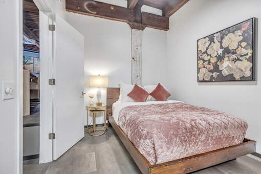 A bedroom with a bed, a lamp, and a painting on the wall.