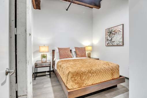 A bedroom with a bed, nightstands, and a painting on the wall.