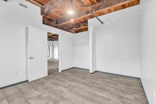 A room with a white door and a wooden ceiling.