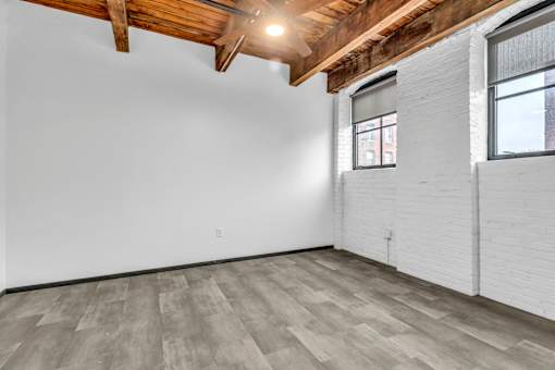 A room with wooden beams on the ceiling and a window on the right wall.